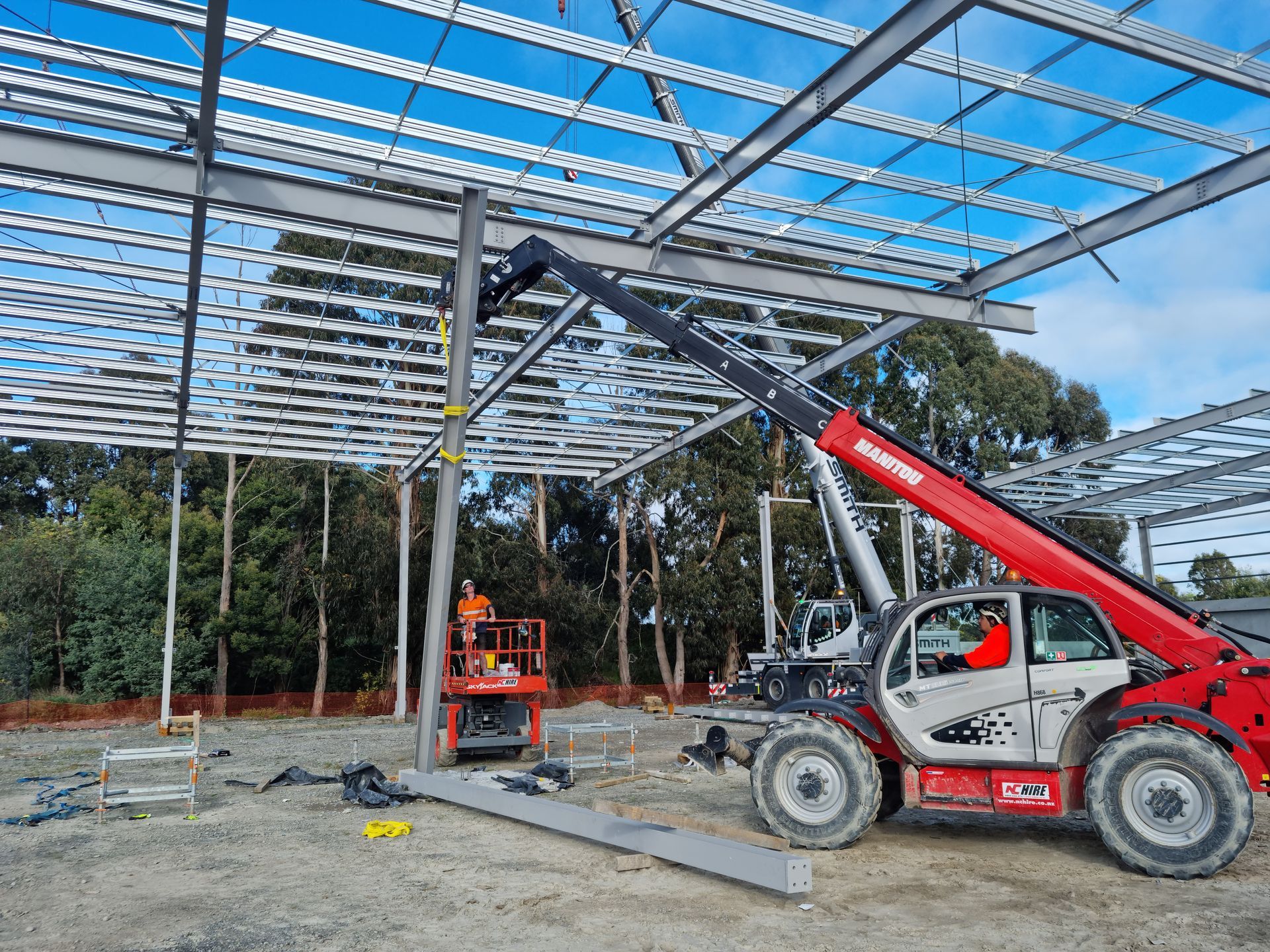 A red and white forklift is working on a building under construction.