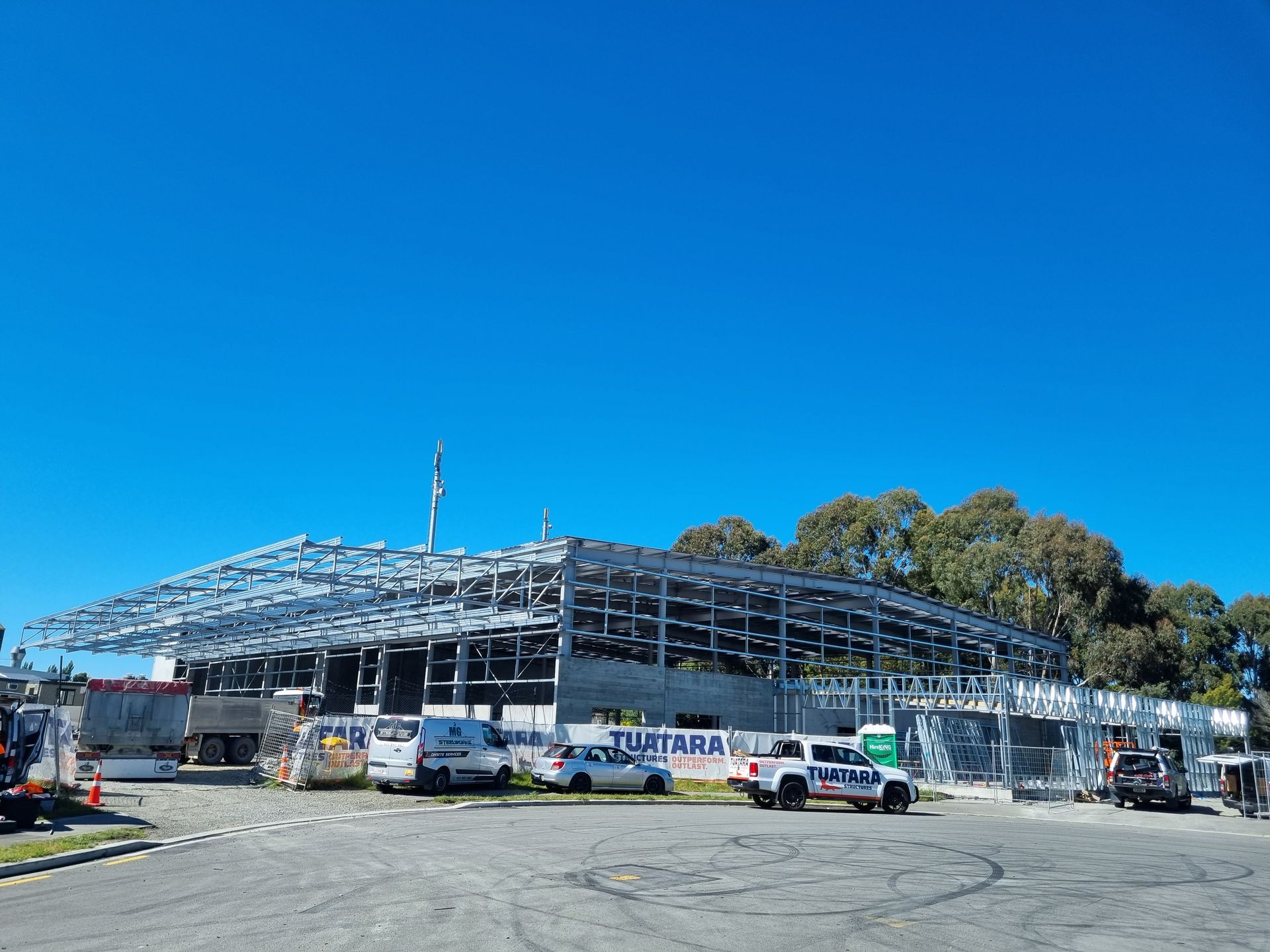 A building under construction with a lot of cars parked in front of it