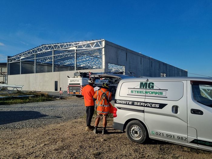 A white van is parked in front of a building under construction.