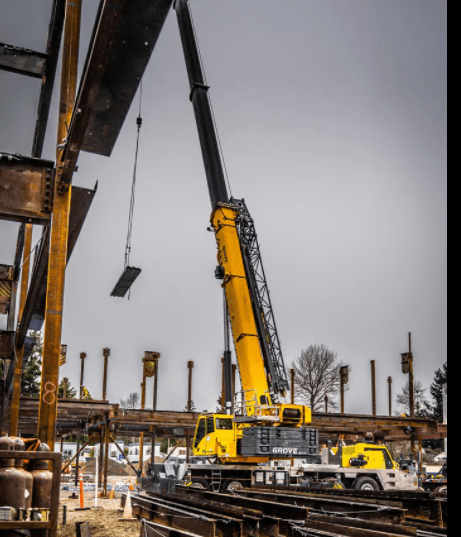 A large yellow crane is working on a construction site