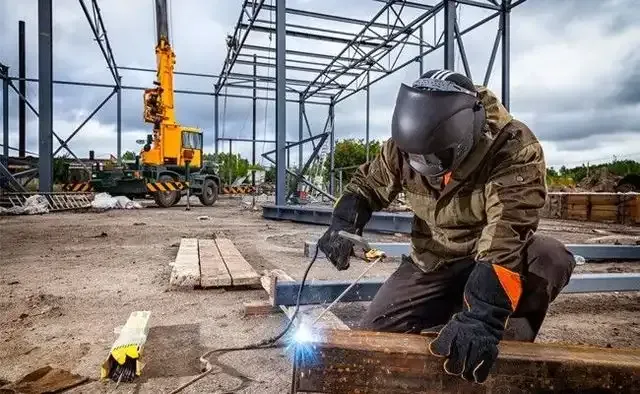 A man is welding a piece of metal on a construction site.
