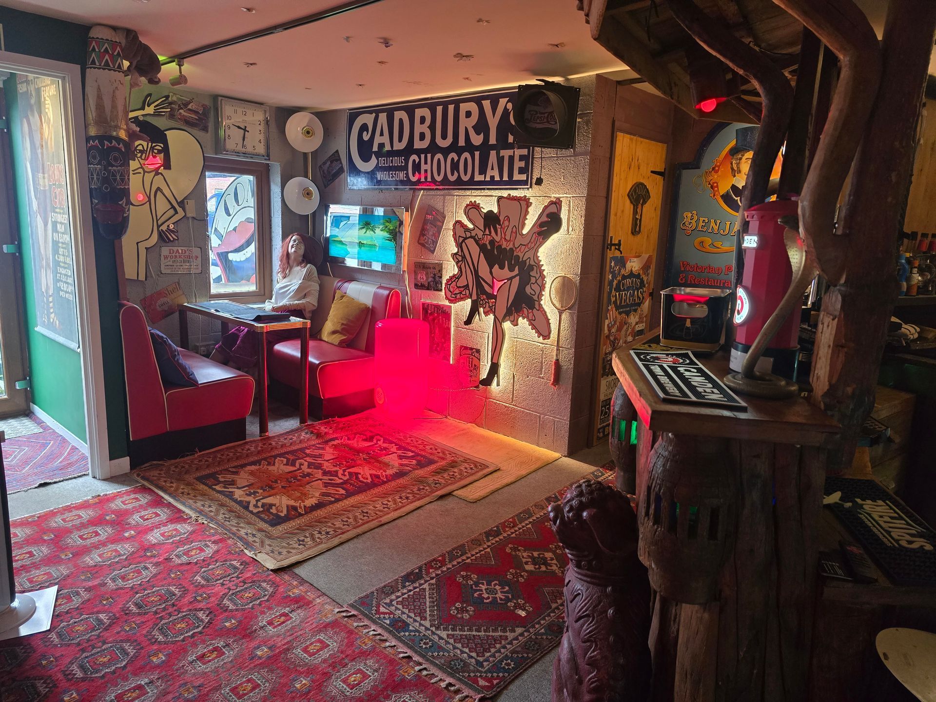 Quirky Cadbury Chocolate-themed room with red seating, patterned rugs, warm lights, and colorful wall art