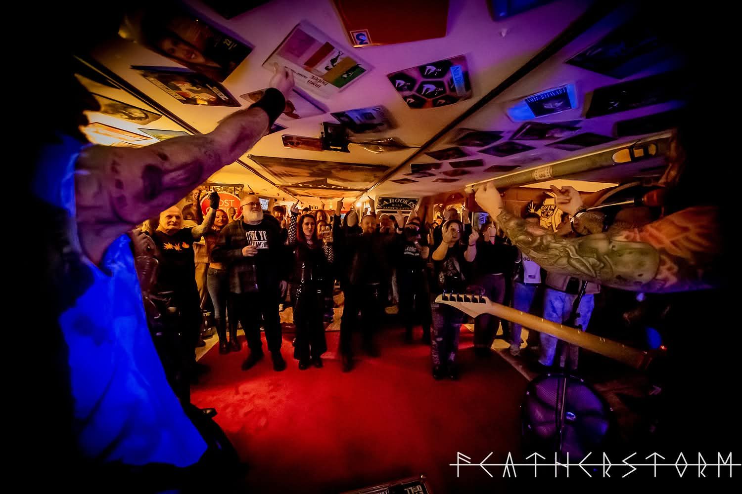 Crowded nightclub with red floor, purple lighting, and a DJ booth under a mirrored ceiling