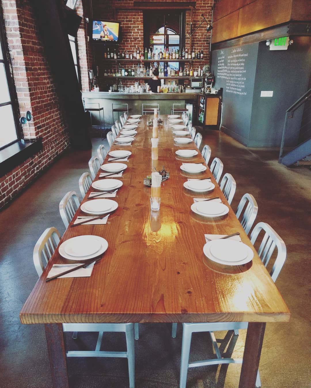 Picture of a long communal table ready to serve 20 guests with the full bar in the background.