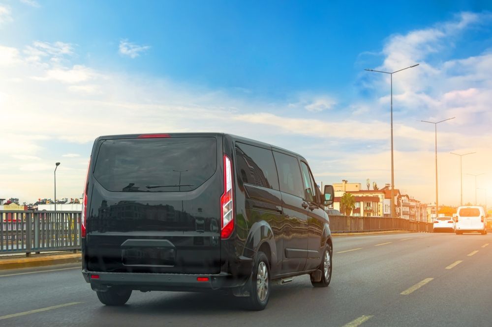 A black van is driving down a city street.