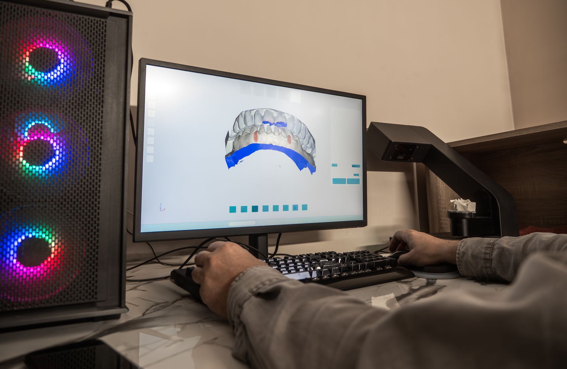 A partial view of a technician using dental CAD software showing a 3D crown model on screen.