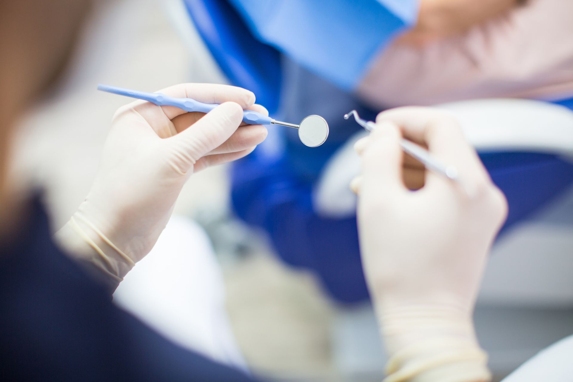 Dentist holding dental tools during dental check-up, close-up view of hands and instruments. 