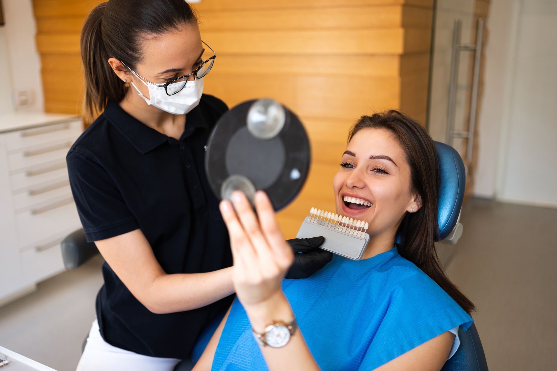 Young patient selects the perfect tooth color using a shade guide during a cosmetic dentistry visit.