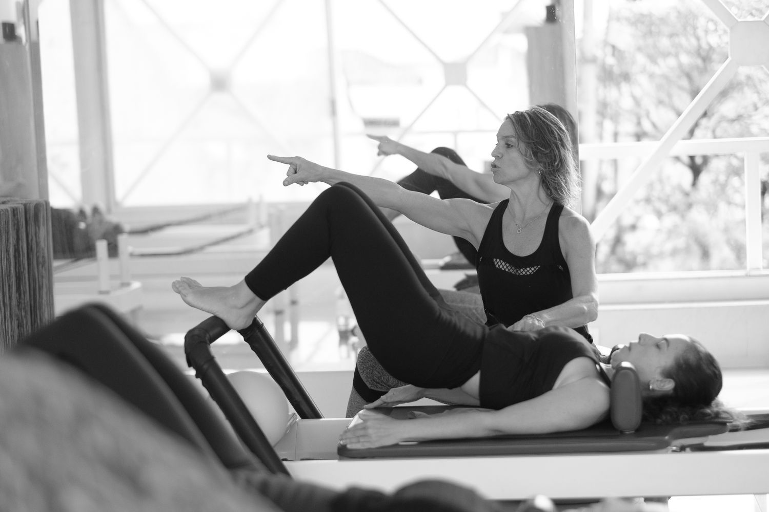 Una mujer le está enseñando a otra mujer cómo hacer pilates en una máquina de pilates.