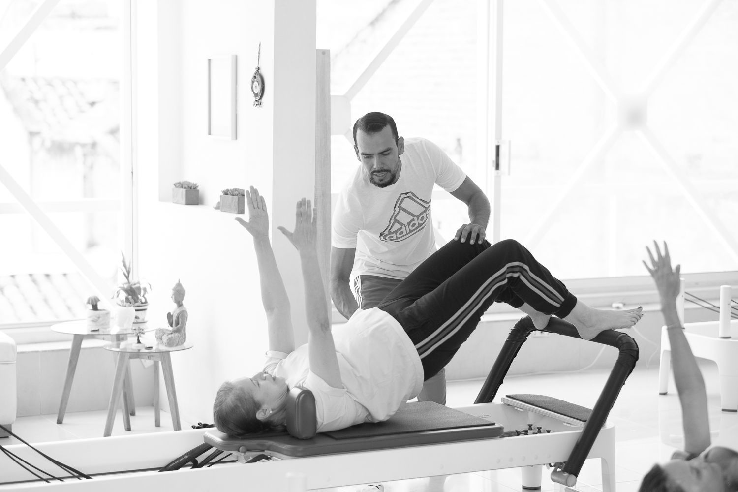 Un hombre está ayudando a una mujer a hacer ejercicios en una máquina de pilates.
