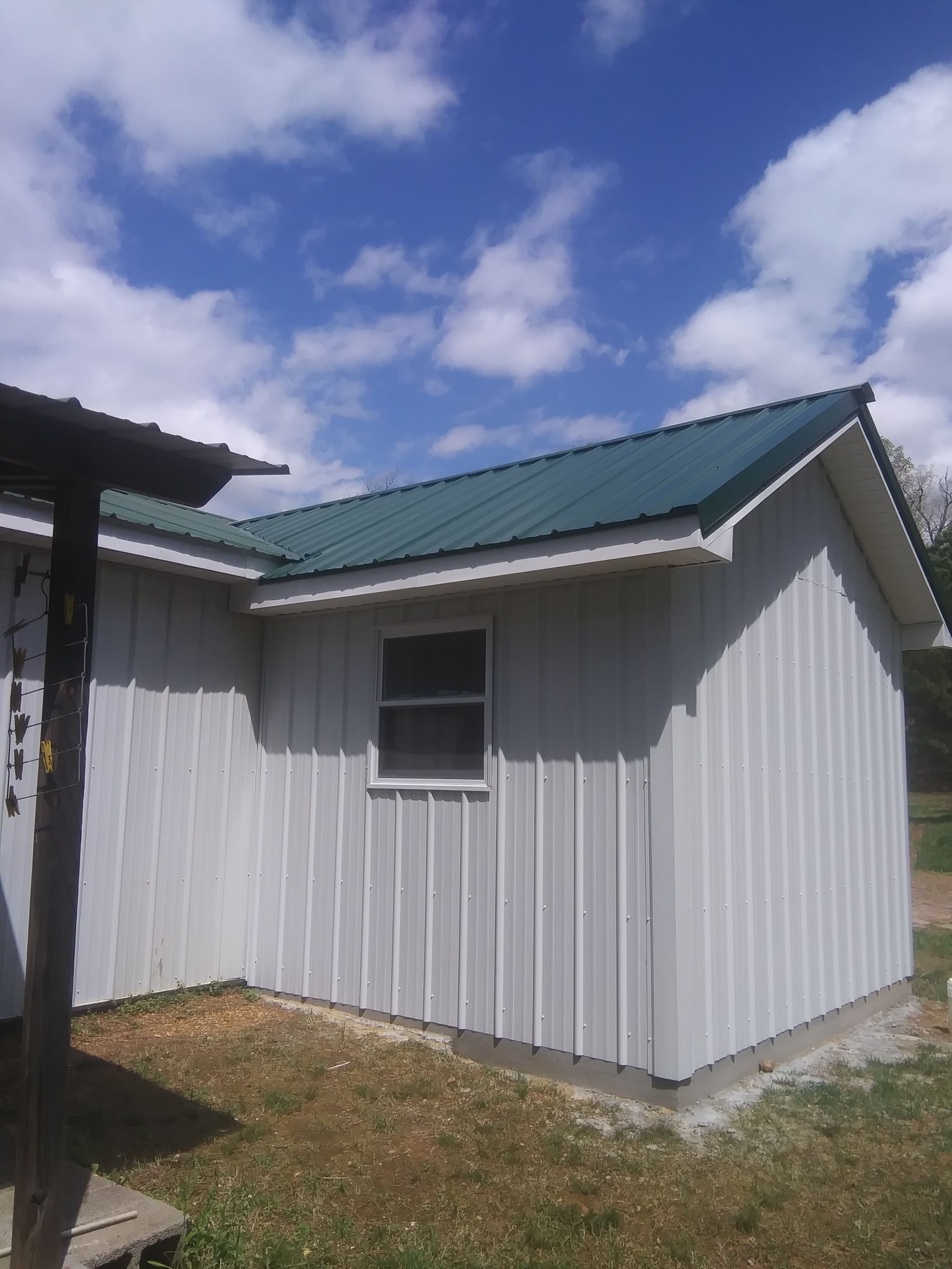 A white building with a green roof and a window