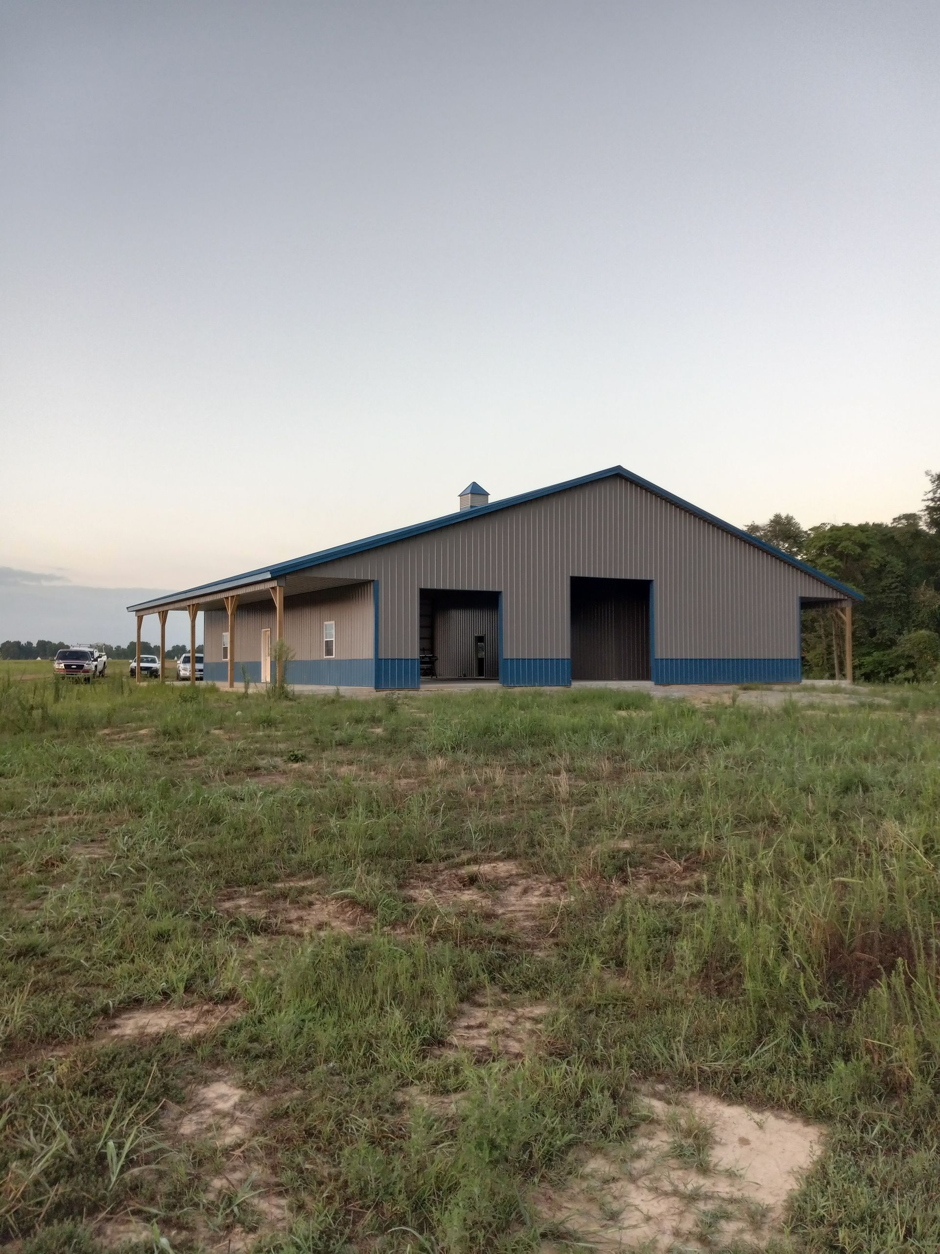 A large barn is sitting in the middle of a grassy field.