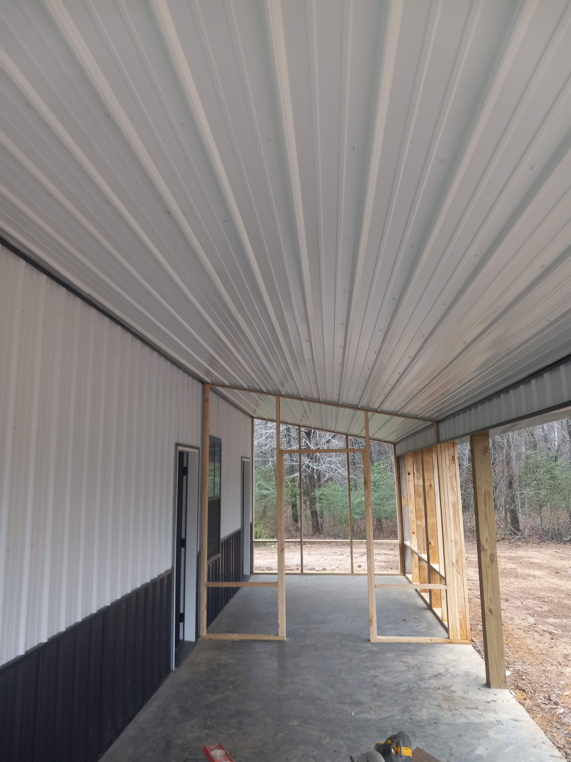 The inside of a building with a metal roof and a concrete floor.