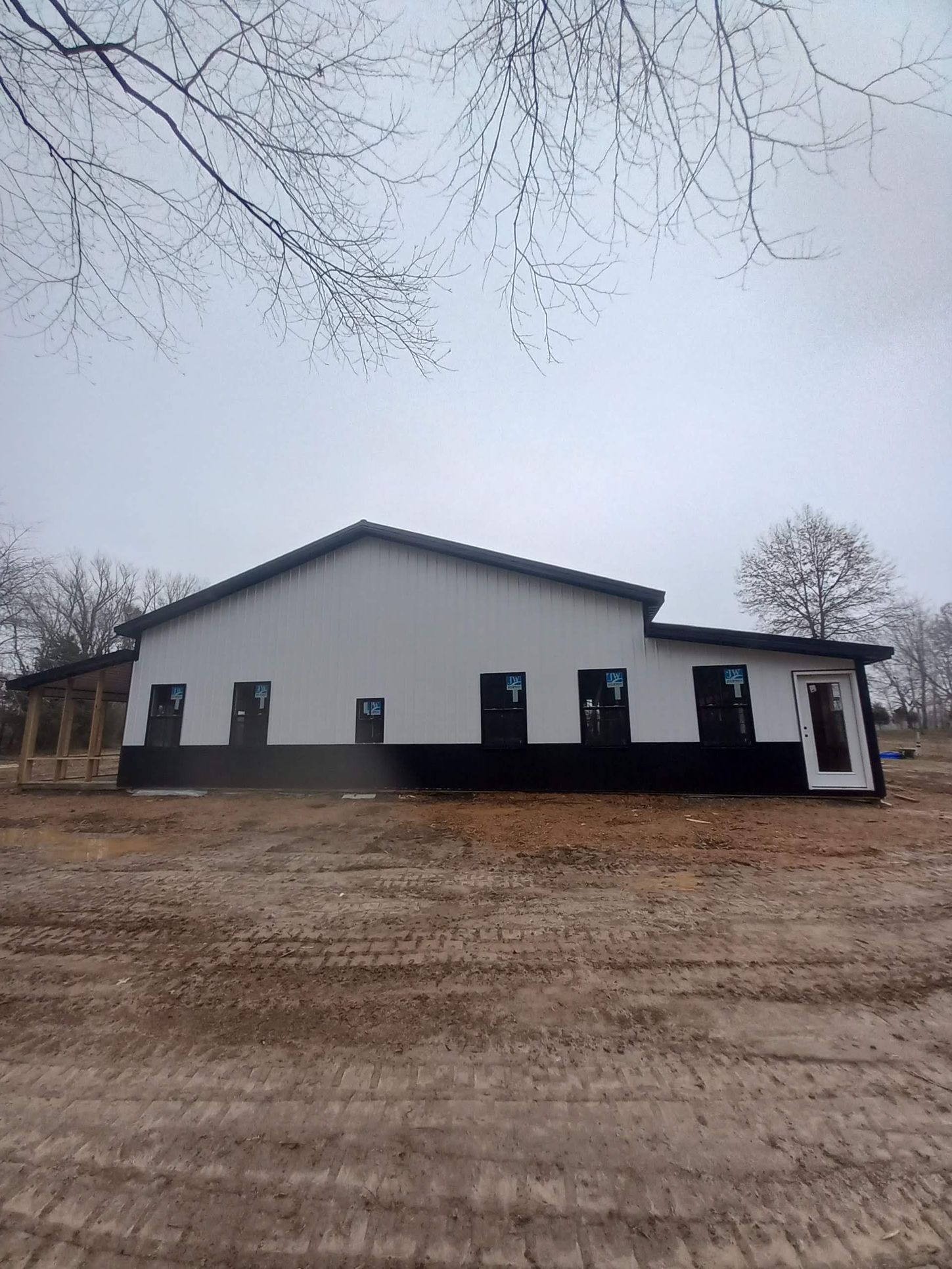 A large white and black building is sitting in the middle of a dirt field.