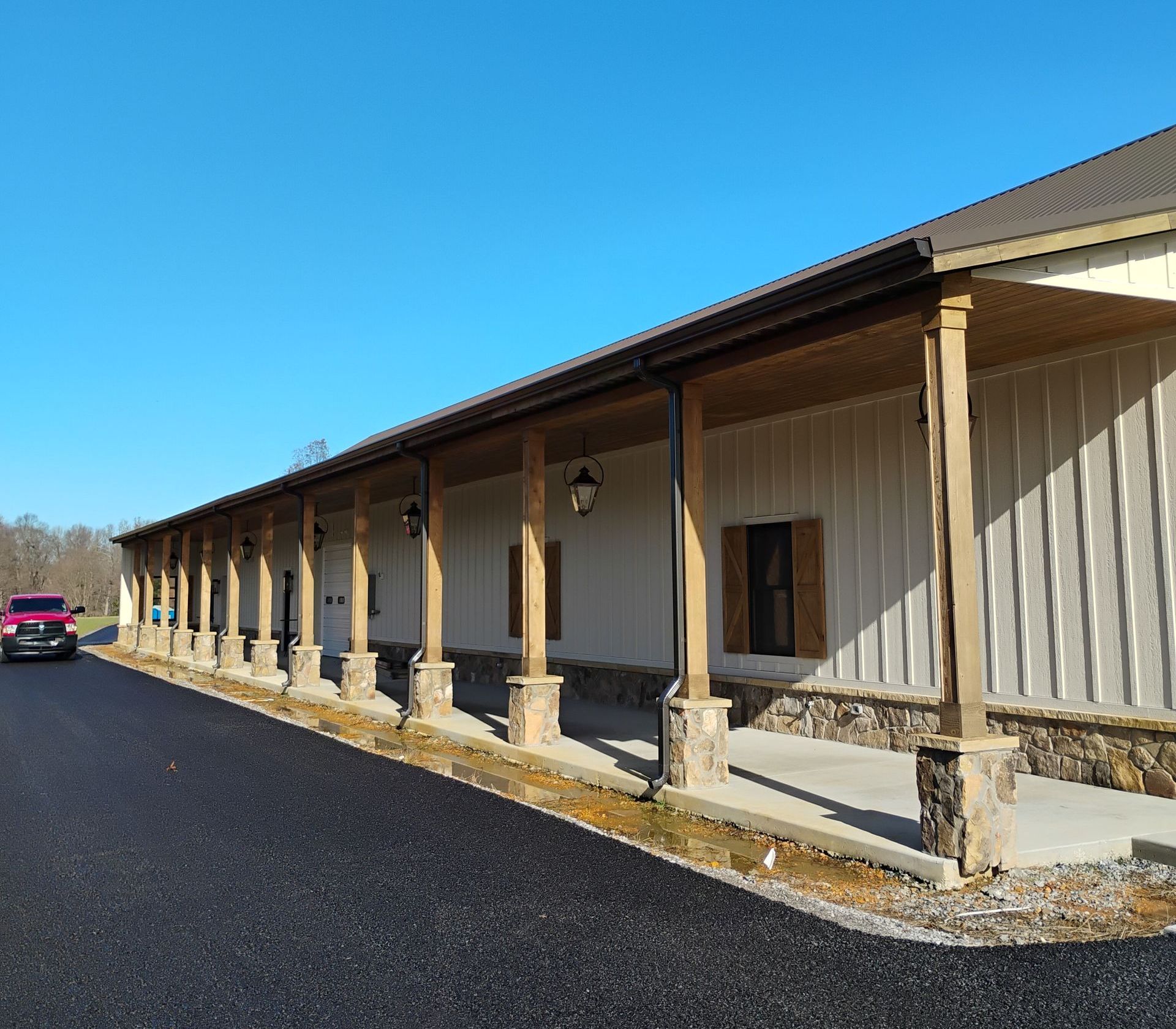 A pink truck is parked in front of a large building with a porch.