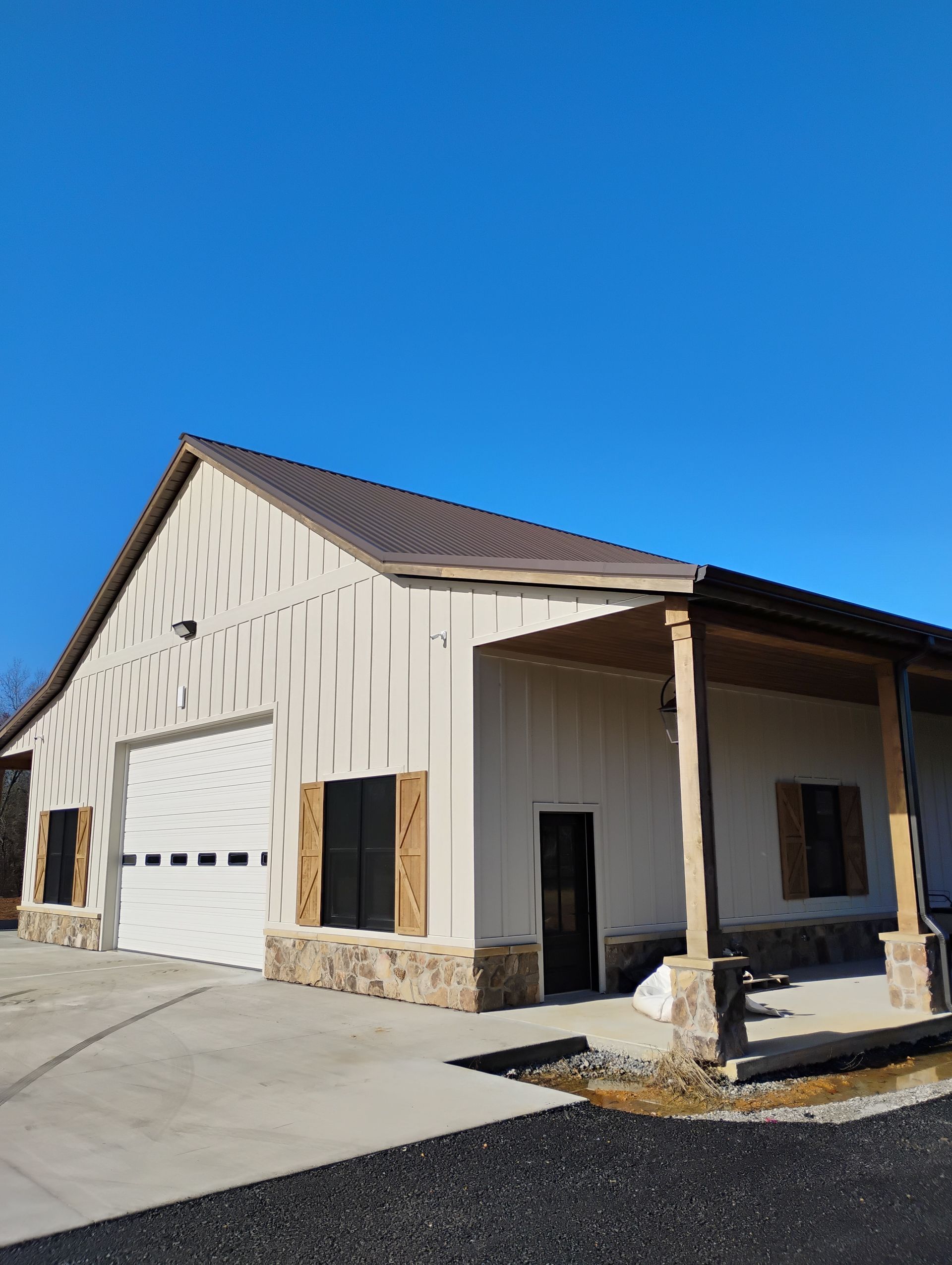 A white house with a brown roof and a porch.