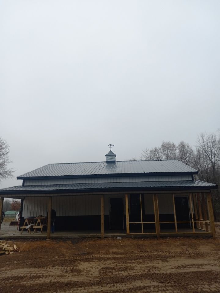 A house with a porch and a metal roof is being built.