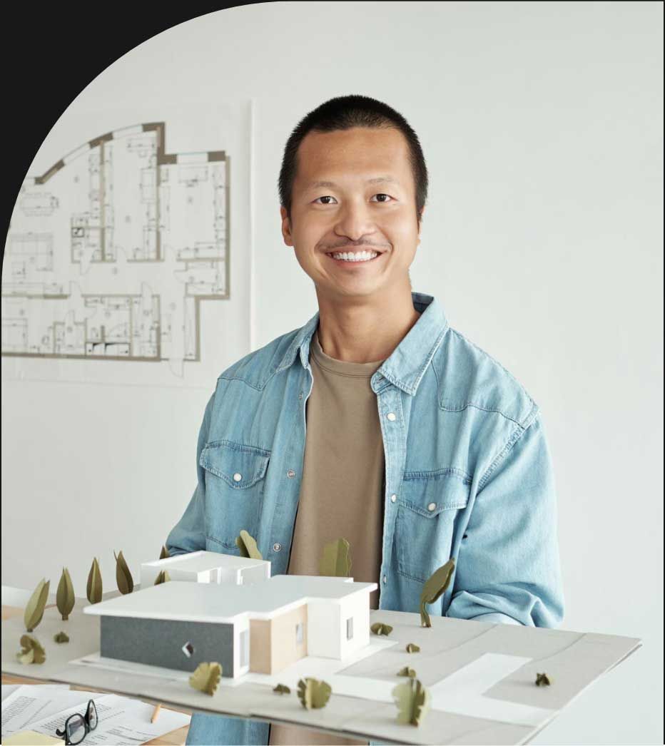 A man in a blue shirt is holding a model of a house.