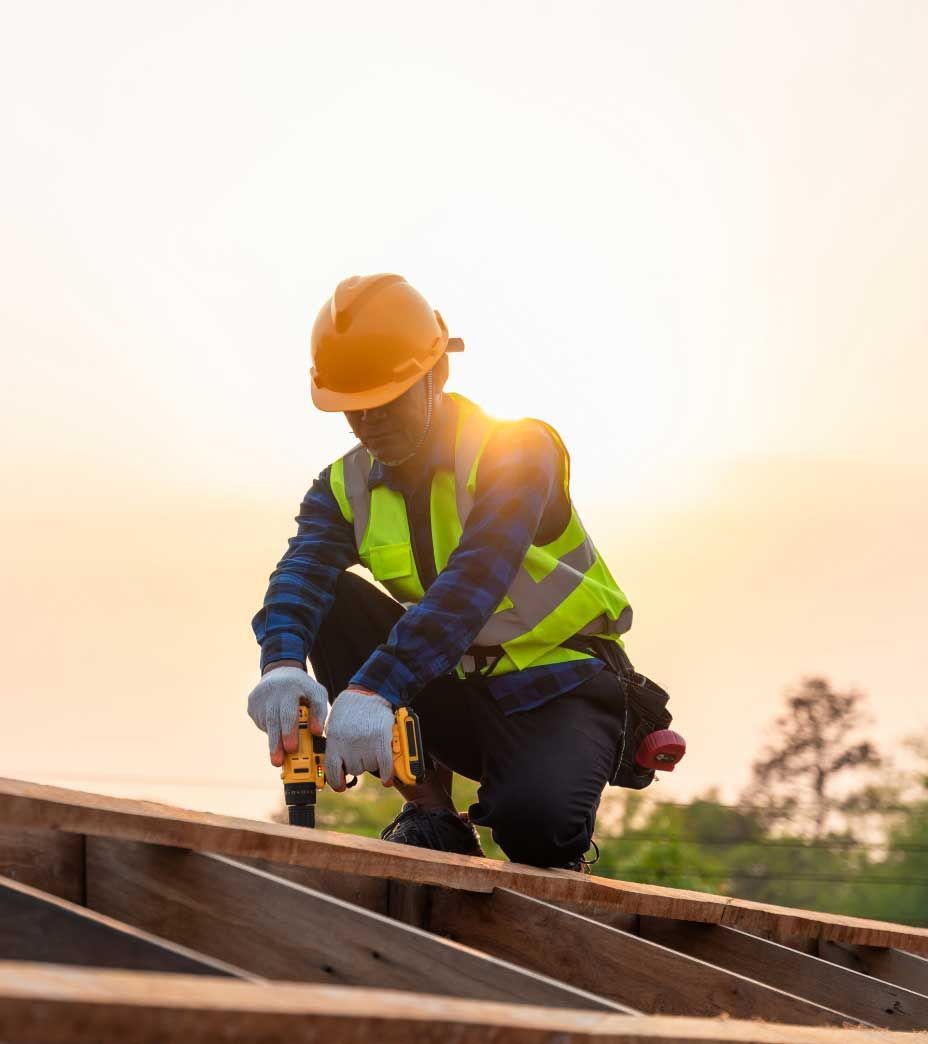 A construction worker is working on a wooden structure with a drill.