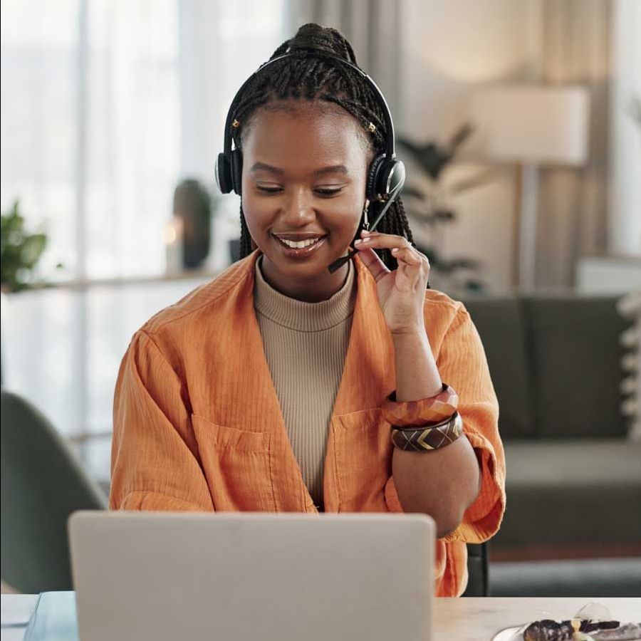 A woman wearing headphones is sitting in front of a laptop computer.