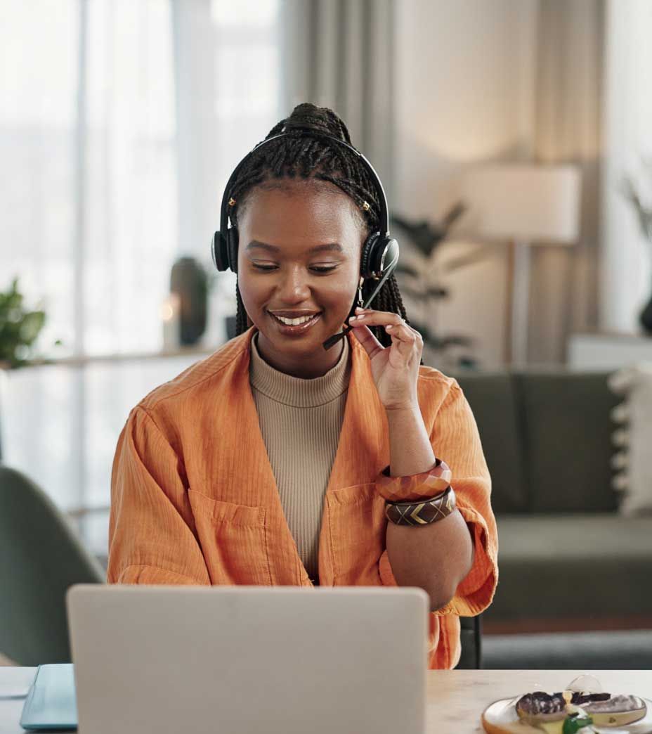 A woman wearing headphones is sitting in front of a laptop computer.