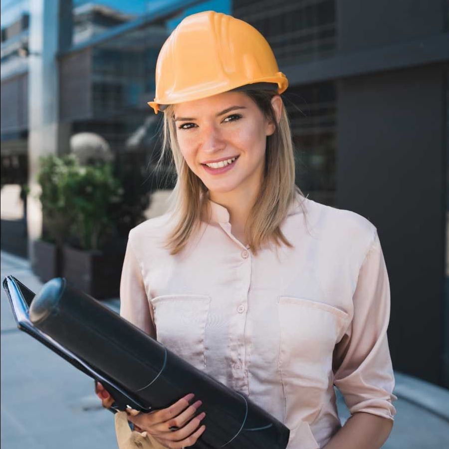 A woman wearing a hard hat is holding a blueprint