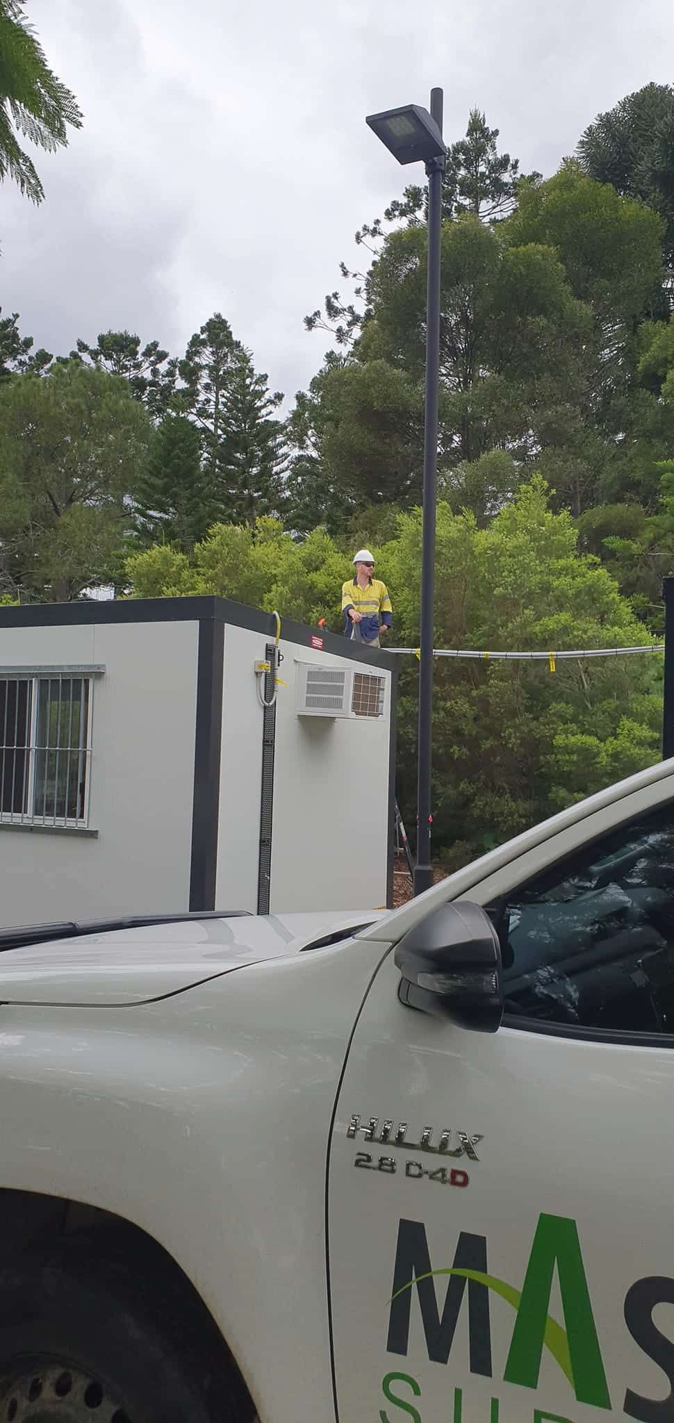 A Man is Standing on Top of a Building Next to a Truck — D.J. Whatley & Son Pty Ltd in Pimpama, QLD