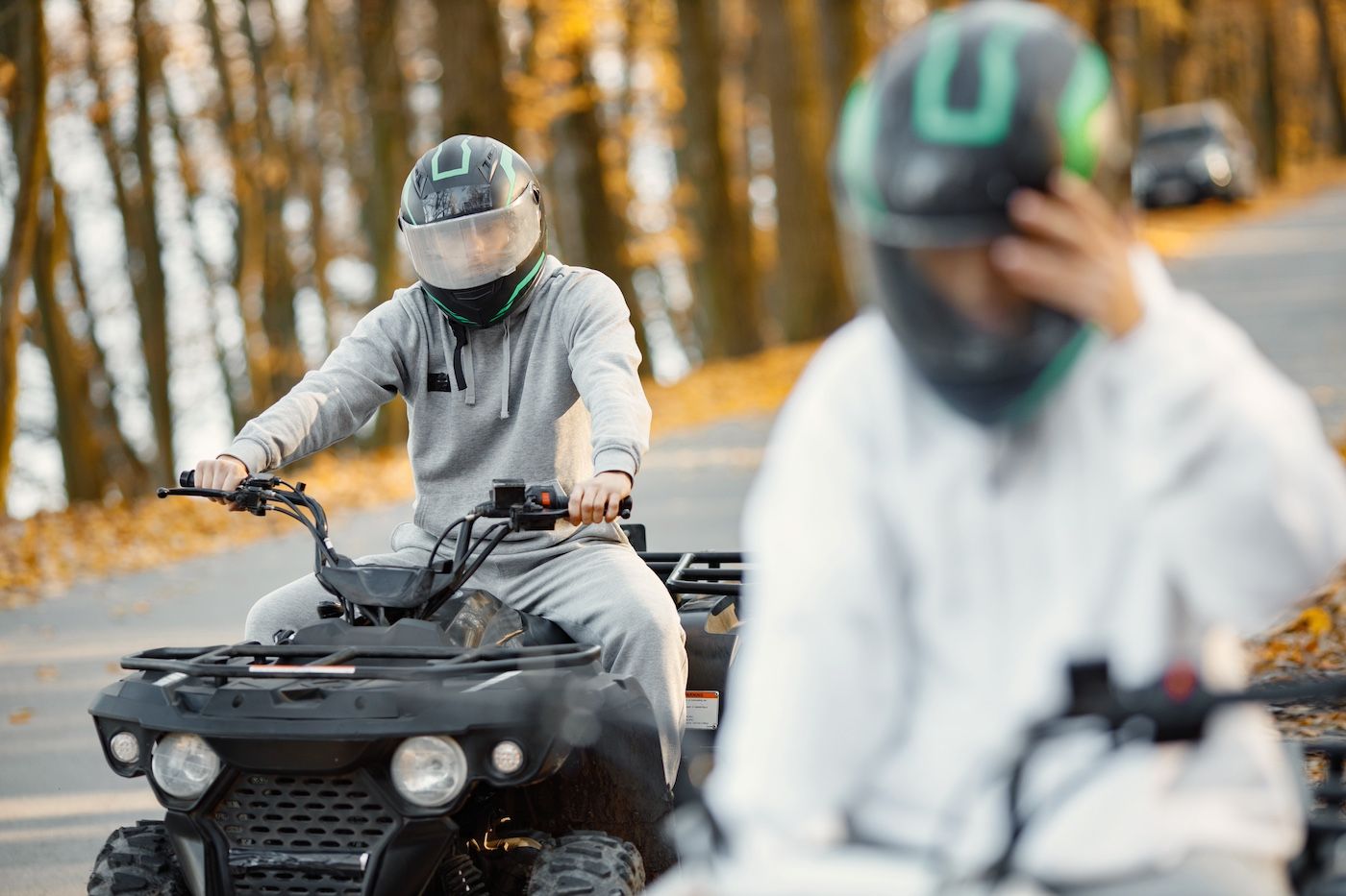 Two people wearing helmets while riding ATVs at Osage Beach, MO.