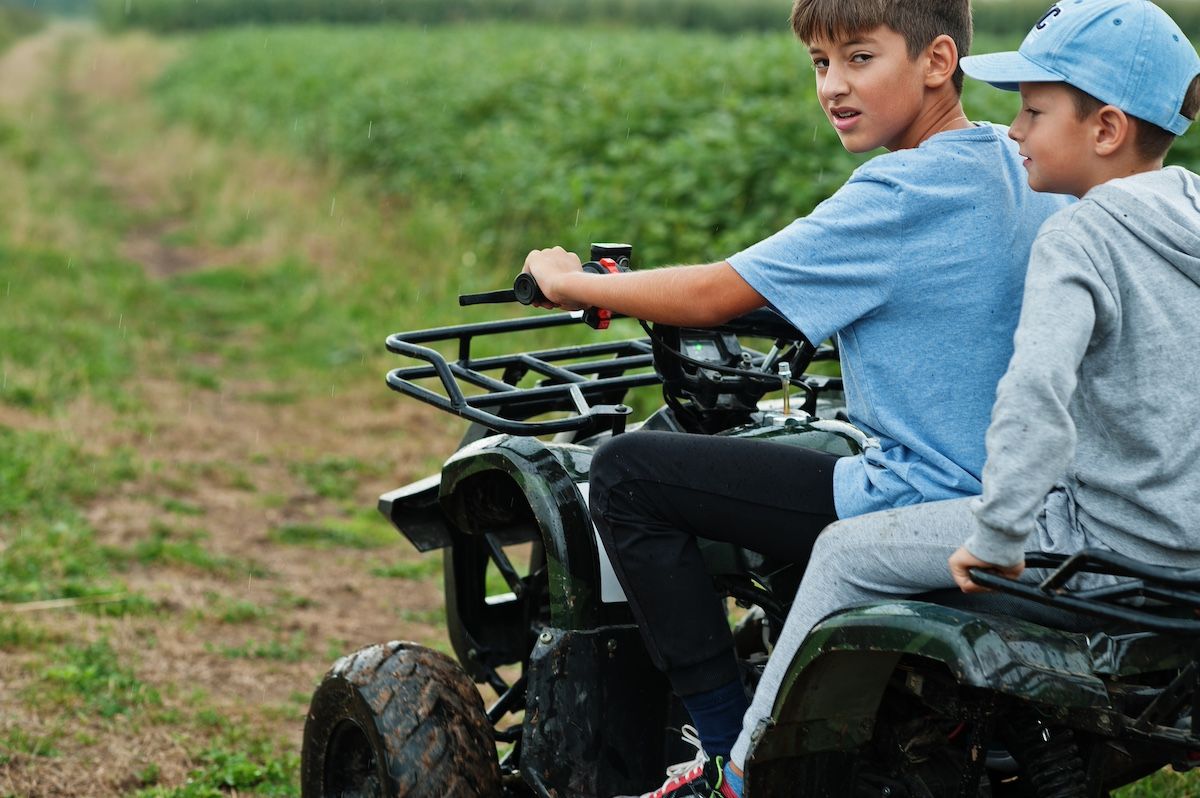 Two Boys Sit On an ATV on a Missouri Trail. Learn About ATV Accident Liability From Our PI Law Firm.