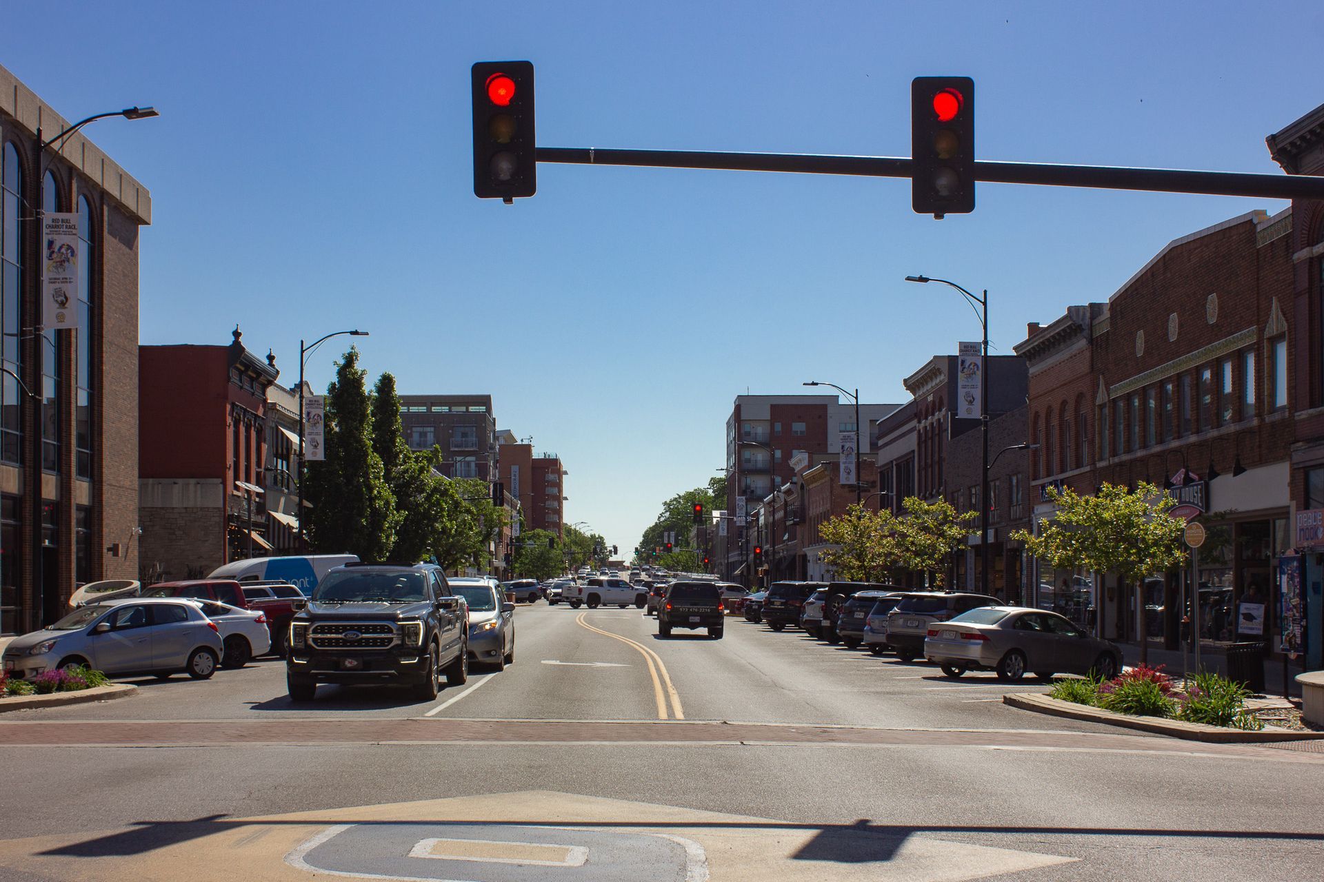 Downtown street with cars stopped at red traffic lights on a sunny day