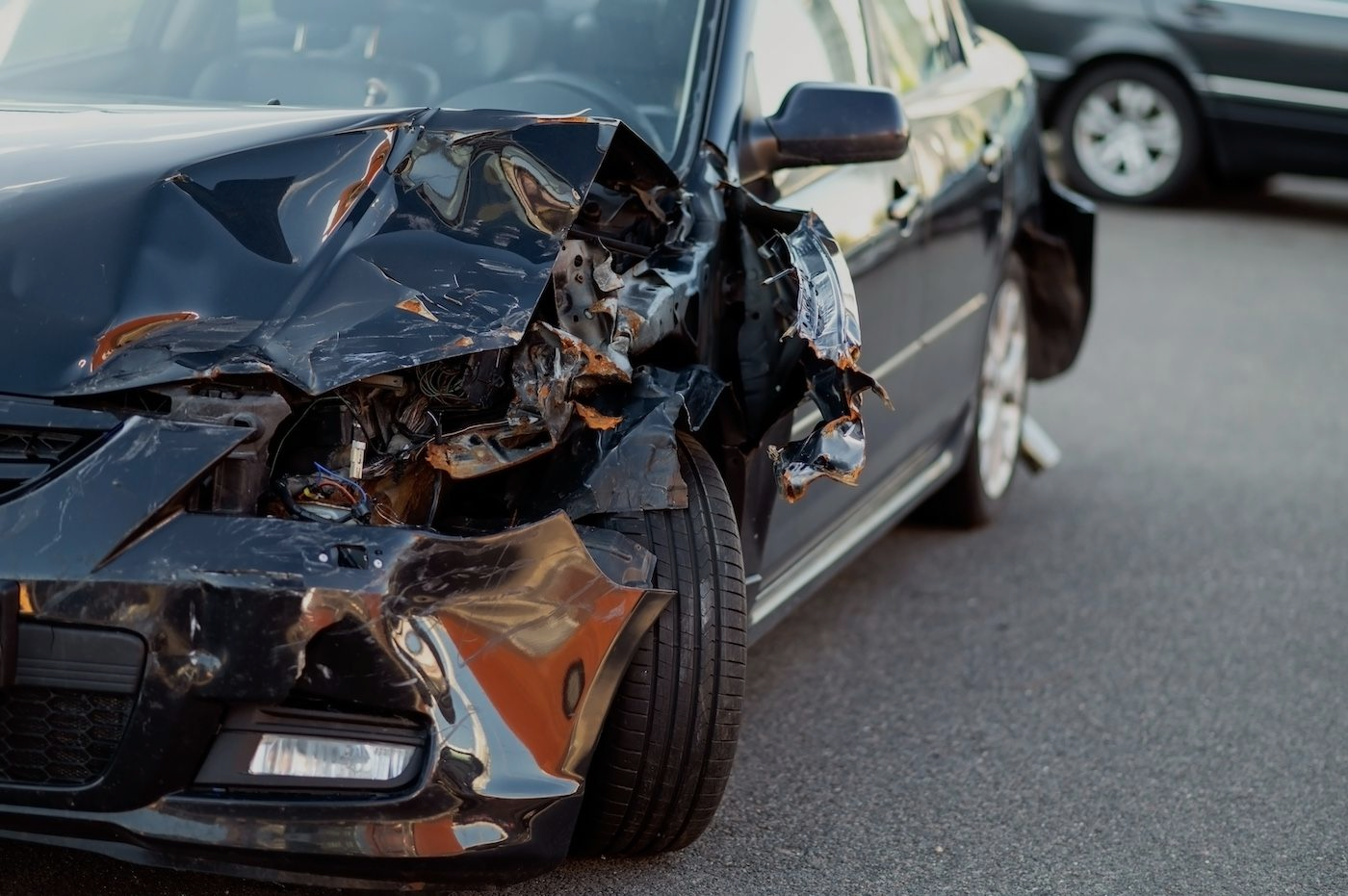 Damaged black car with crumpled front end after a collision on a road