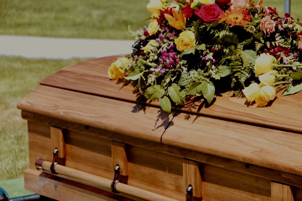 A Wooden Coffin With a Colorful Bouquet of Flowers on Top. Duckworth Injury Law Wrongful Death Case.