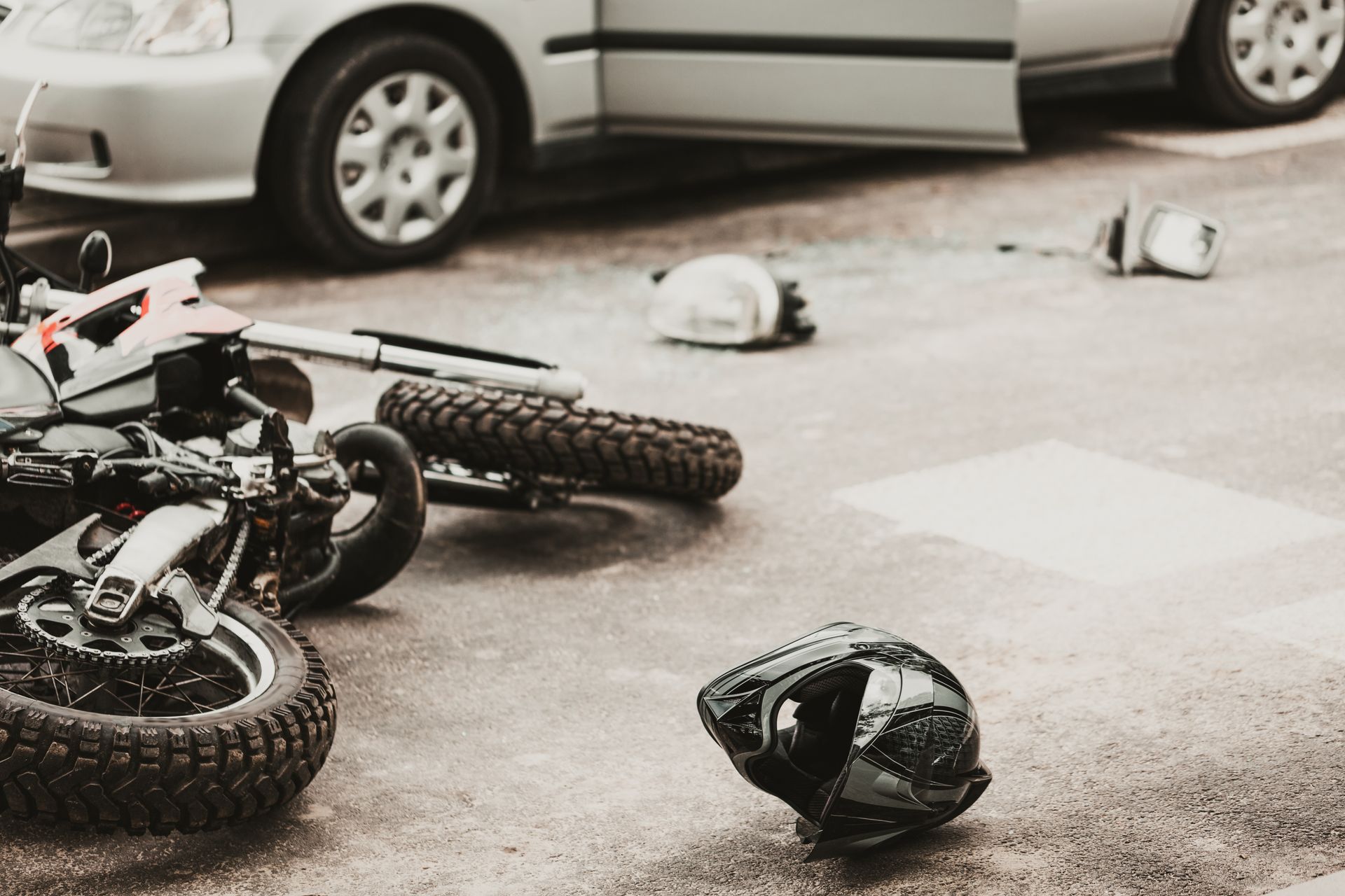 A Motorcycle Lying on It’s Side by a White Car. Call Duckworth Injury Law for Car Accident Help.