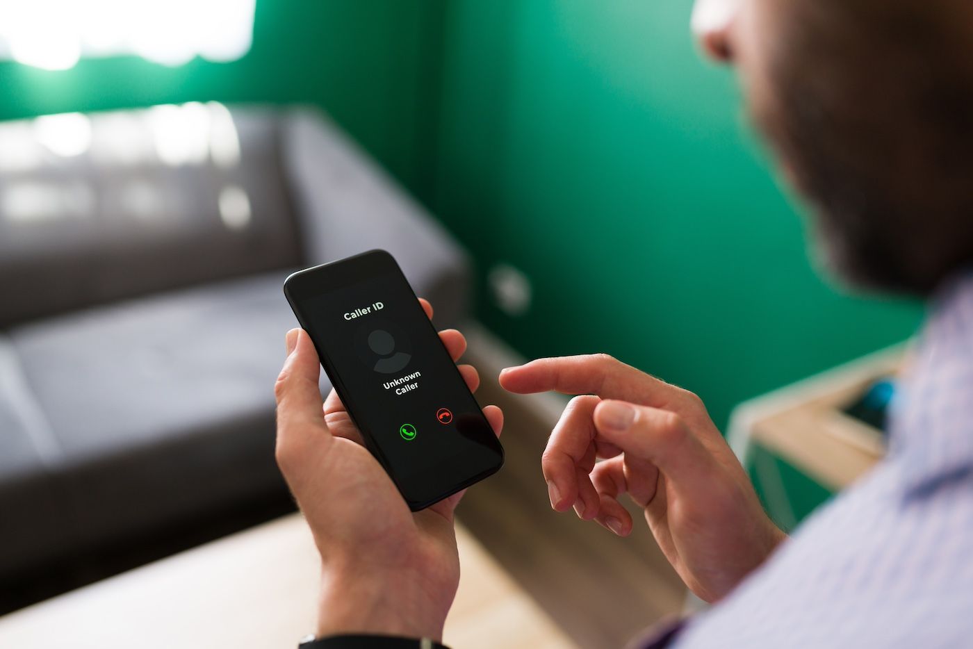 Person holding smartphone with incoming call screen, green and gray background.