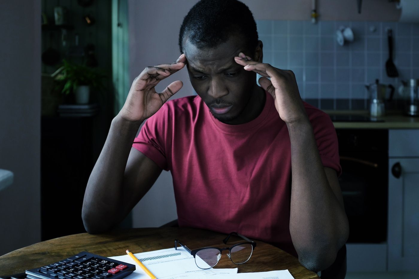A man looks stressed out as he looks at bills at his kitchen table.