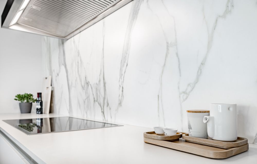 A kitchen counter with a stove top oven and a marble wall.