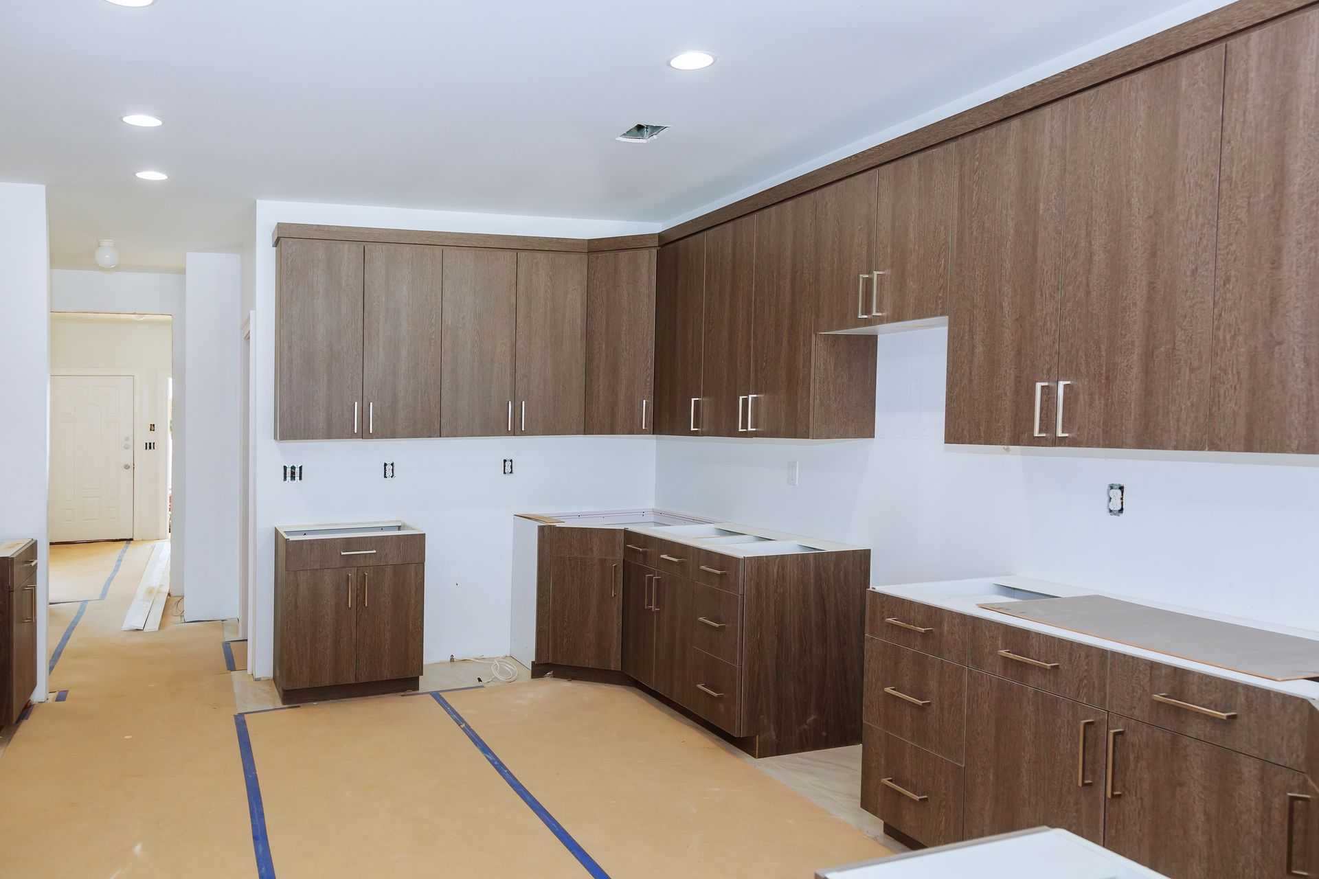 A kitchen under construction with wooden cabinets and white counter tops.