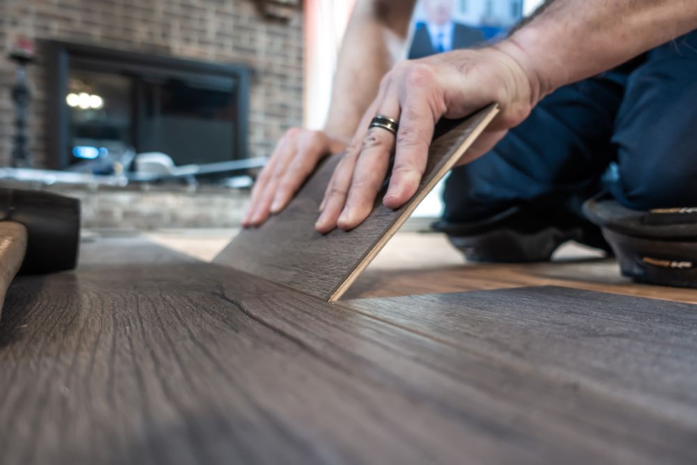 A man is installing a wooden floor in a living room.