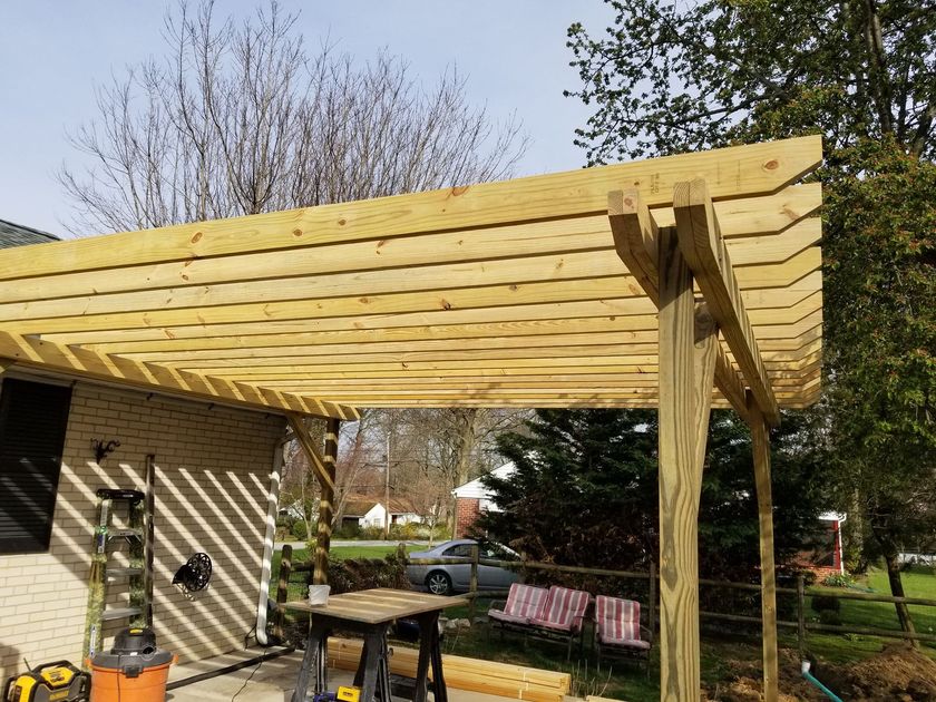 a wooden pergola is being built in the backyard of a house