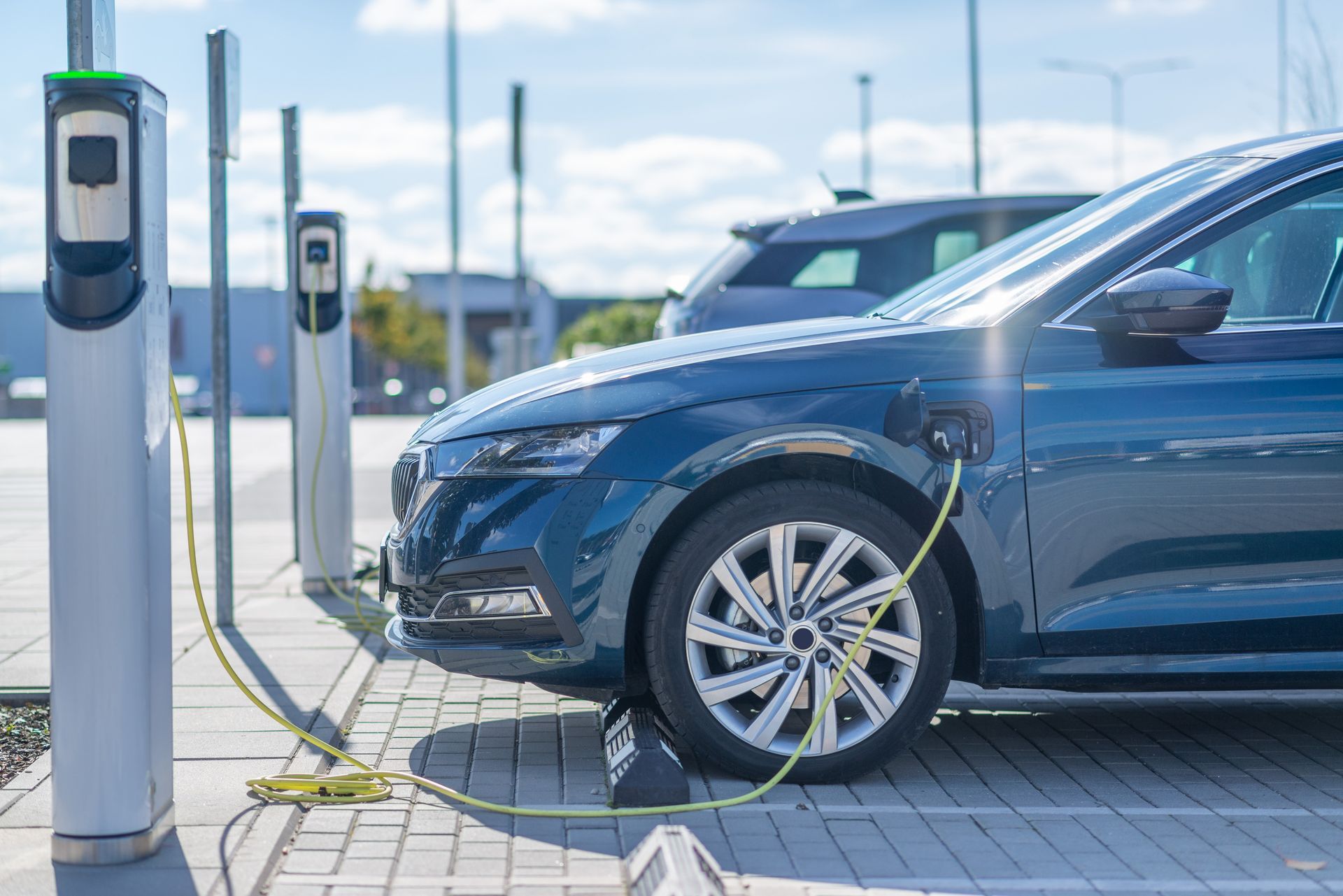 A blue electric car is being charged at a charging station.