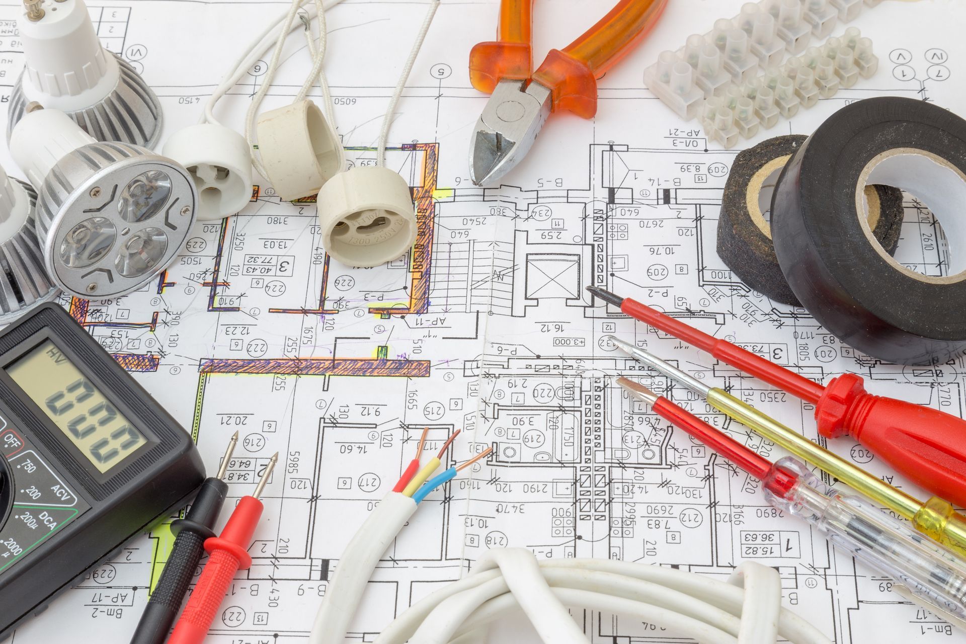 An electrician 's tools are laid out on top of a blueprint