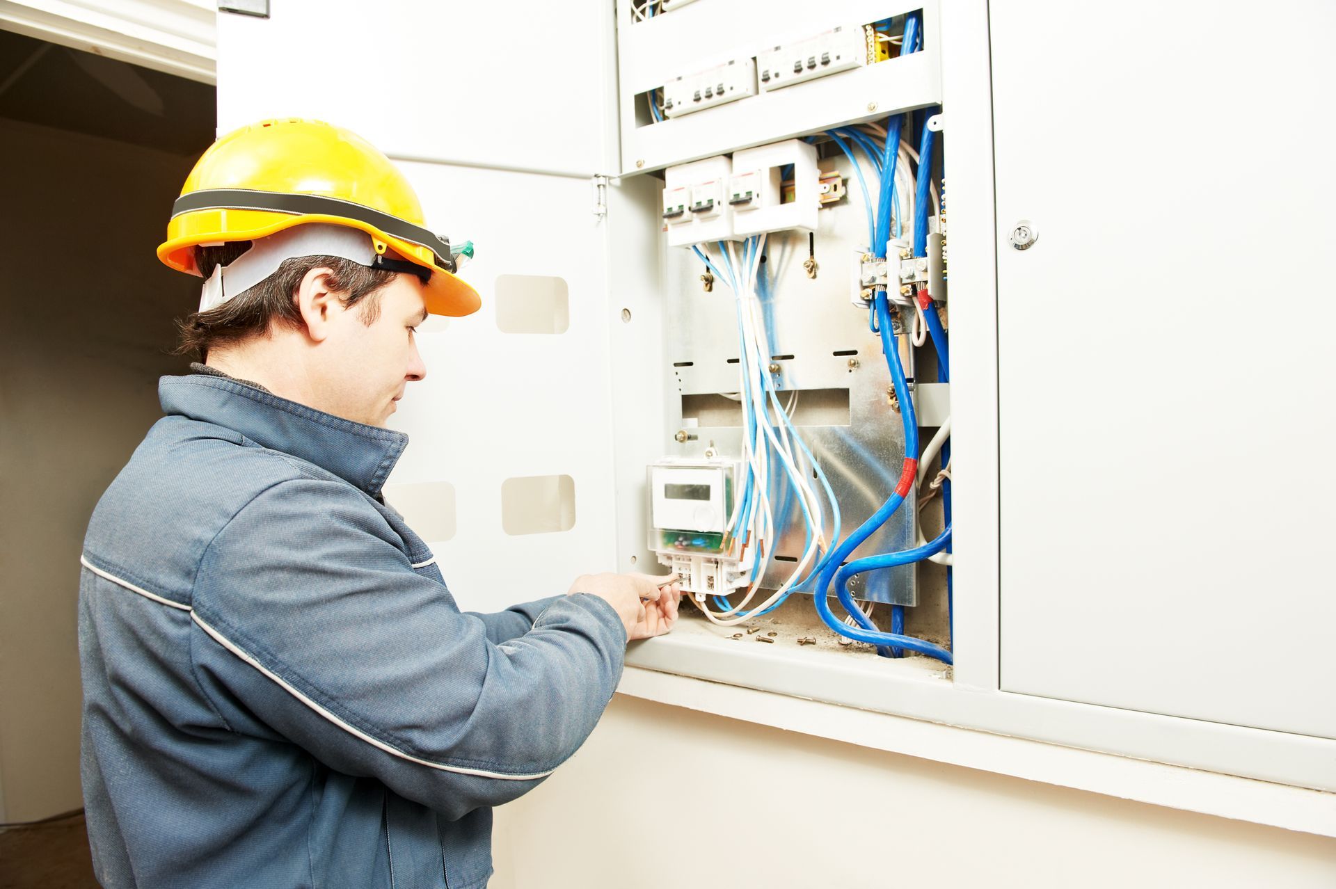 A man in a hard hat is working on an electrical box.