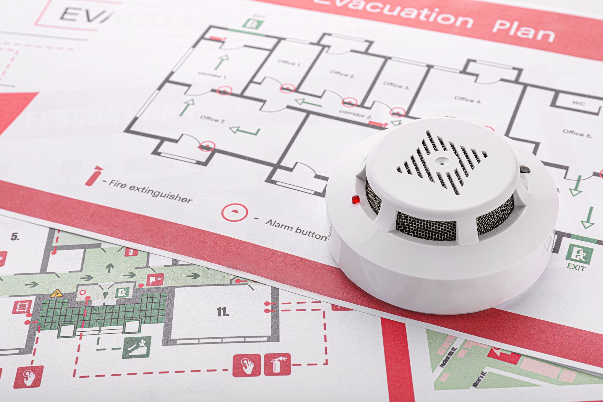 A smoke detector is sitting on top of an evacuation plan.