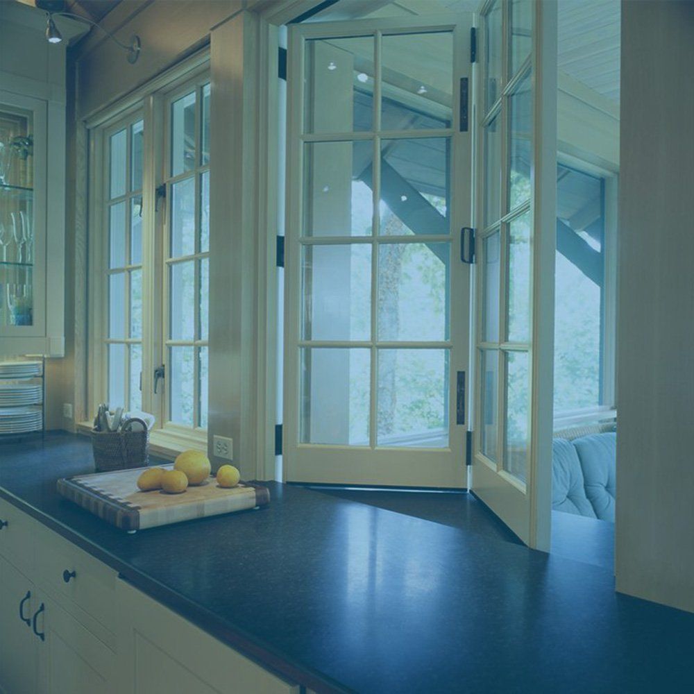 Kitchen with windows and door. Lemons on a cutting board, dark countertop. Light pouring in.