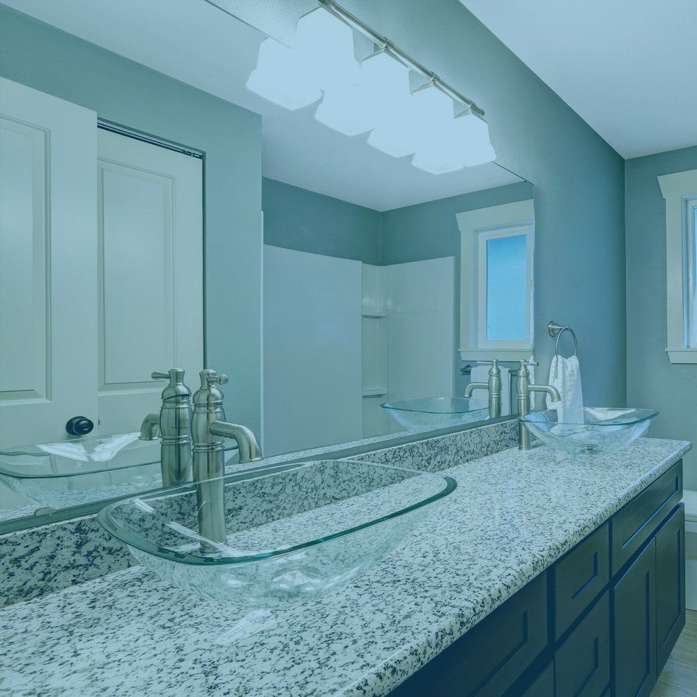 Bathroom with double sinks, glass bowls, granite countertop, large mirror, and overhead lighting.