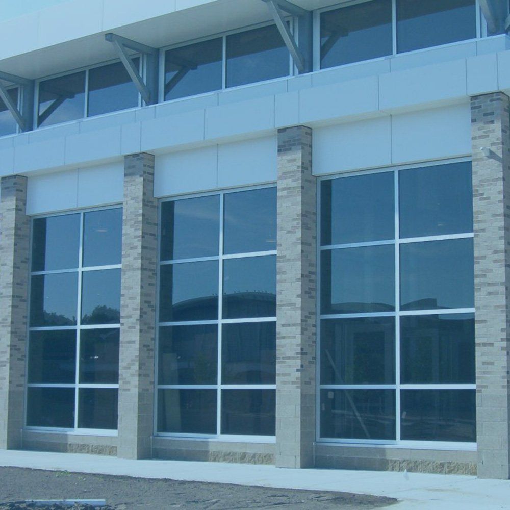 Exterior of a modern building with large glass windows and brick columns.