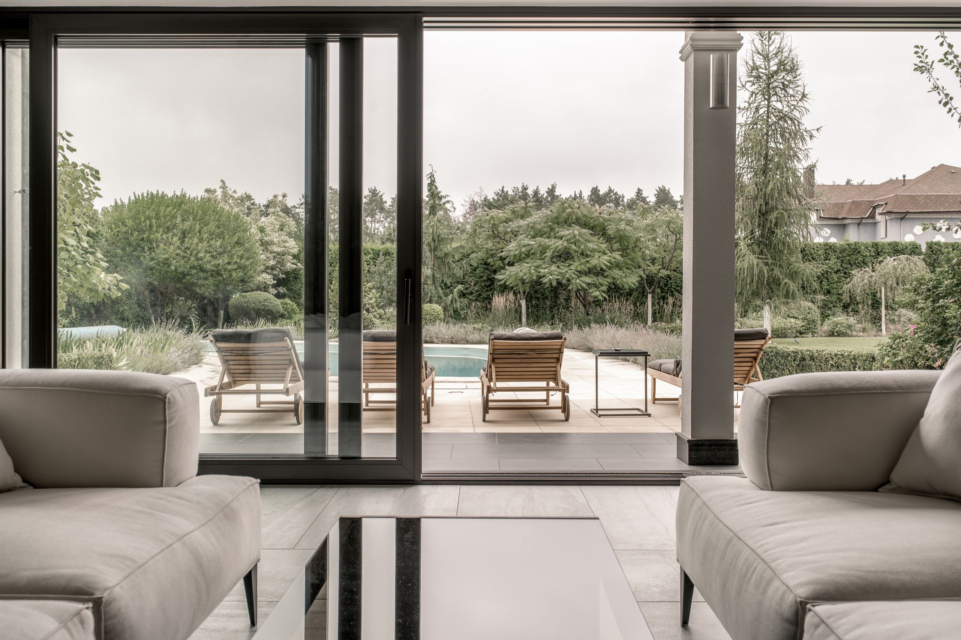 Wooden front door with sidelights, under a porch with gray siding and brick accents.