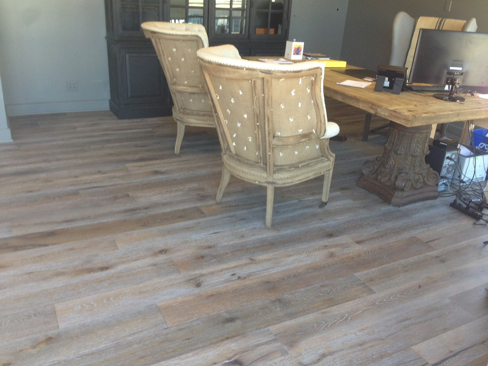 Light wood-look flooring in a room with antique chairs and a rustic table.