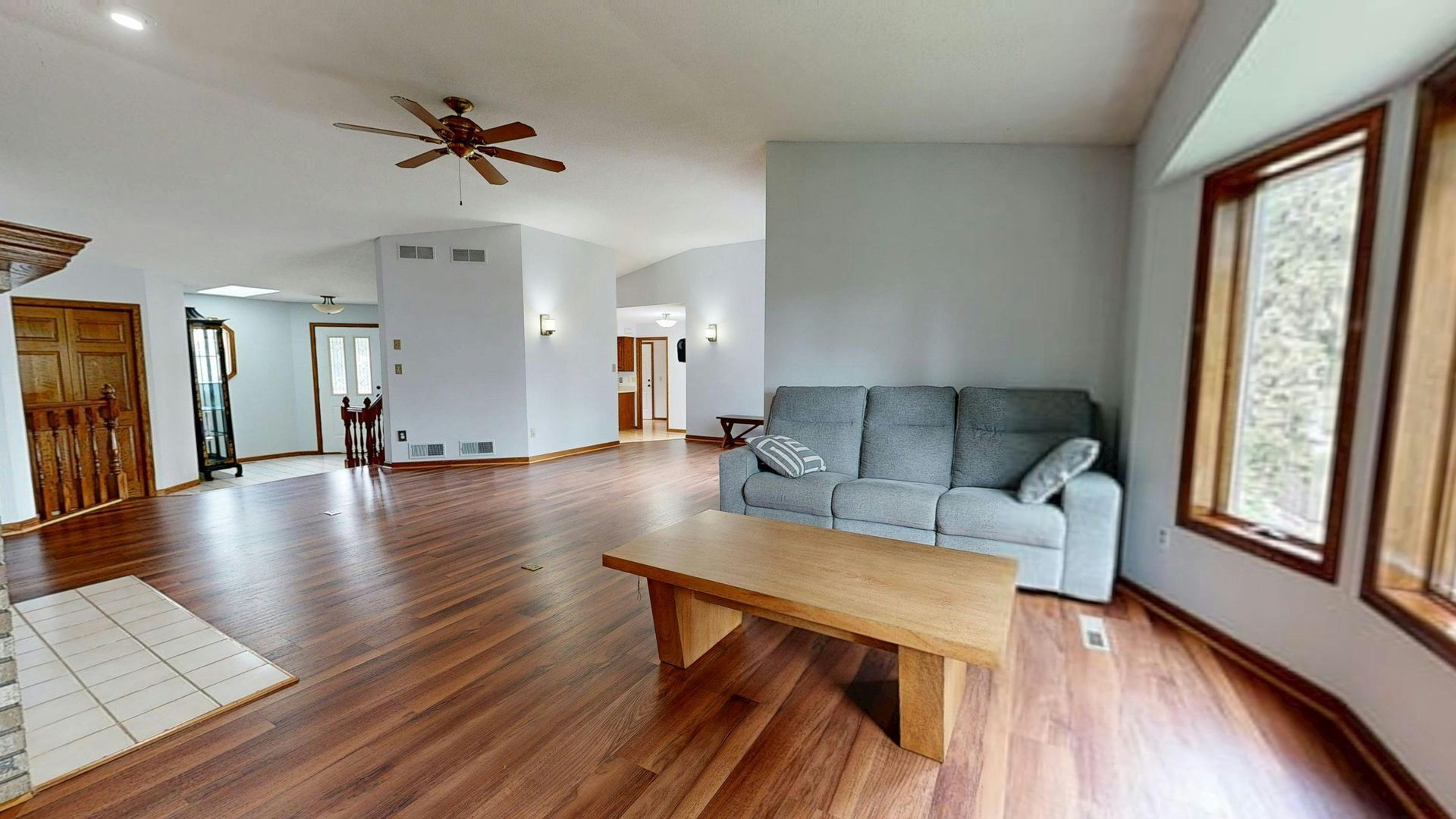 Light wood kitchen with island, cabinets, shelves, and window seat.