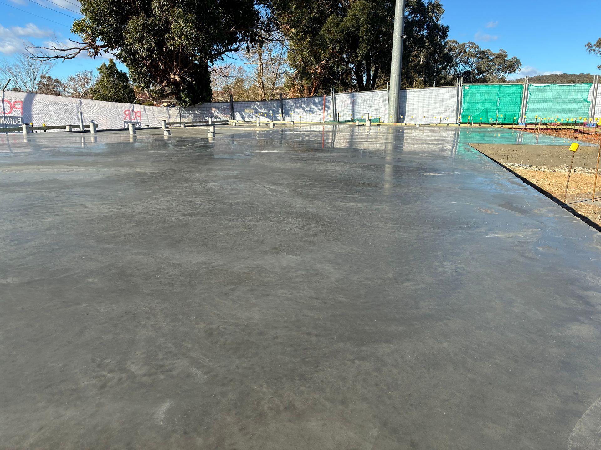 A worker uses a bull float to smooth freshly poured concrete on a sidewalk under construction — Complete Concreting Riverina In Ashmont, NSW